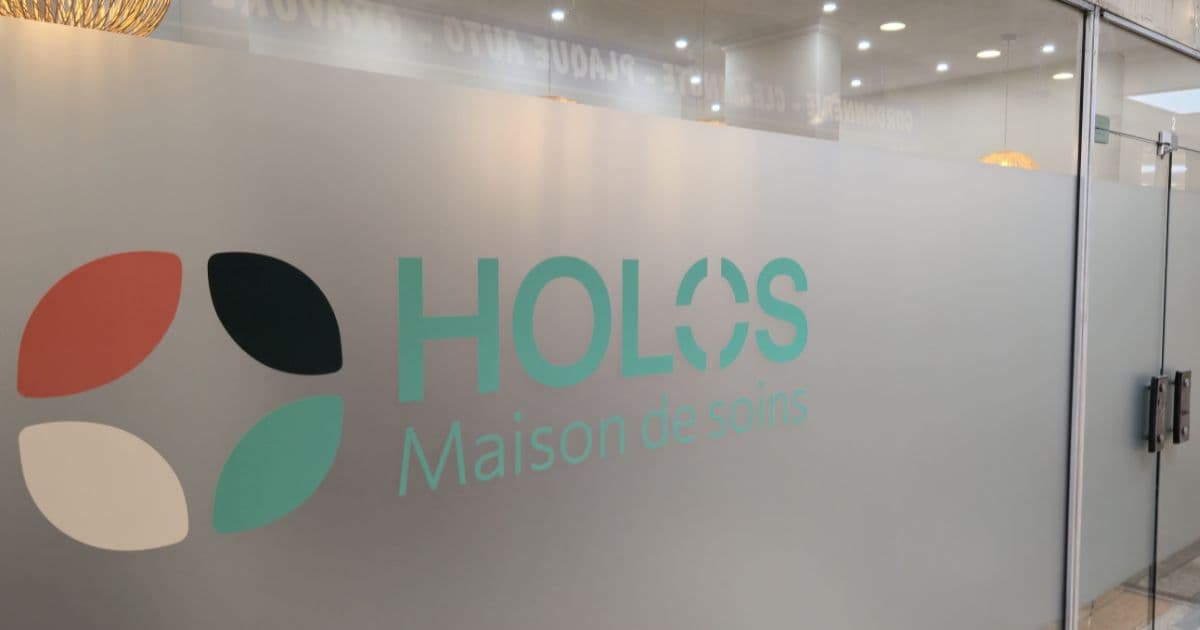 Entrée du local : cloison vitrée portant le logo HOLOS — Maison de soins